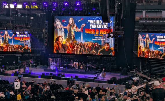 The stage at TD Garden with screens showing "Weird Al's" Bigger & Weirder tour poster.